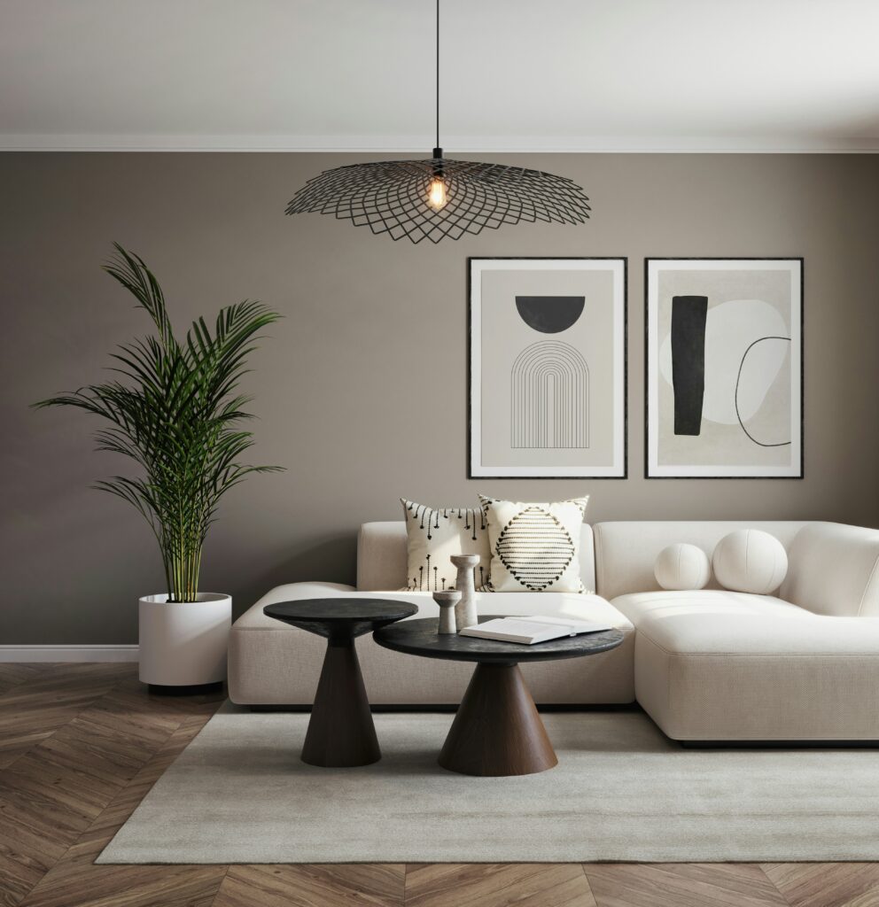 Modern eingerichtetes Wohnzimmer mit beigem Sofa, minimalistischer Wandkunst, schwarzen Couchtischen und ruhiger Farbpalette